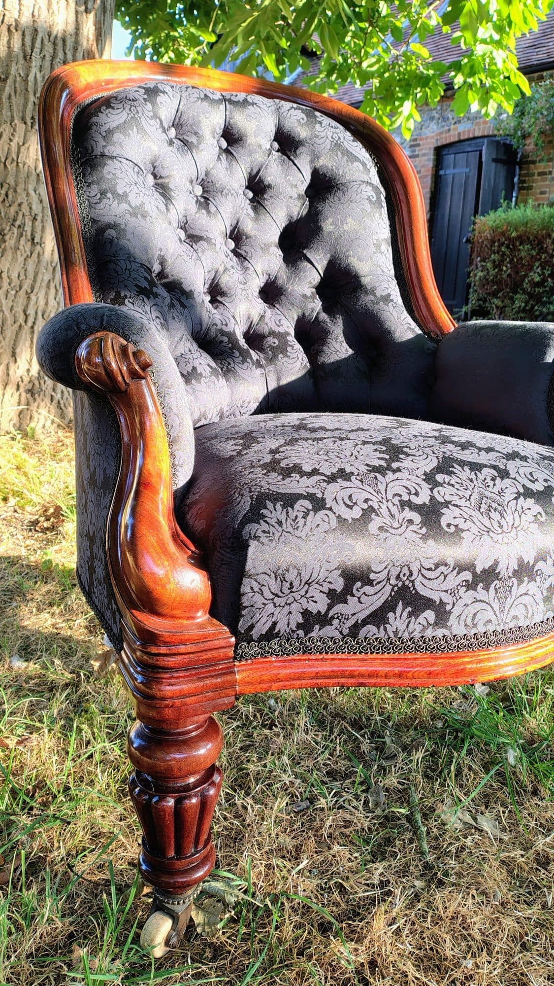 The deep-buttoned inside back and carved arm of Alexandra Brady's armchair