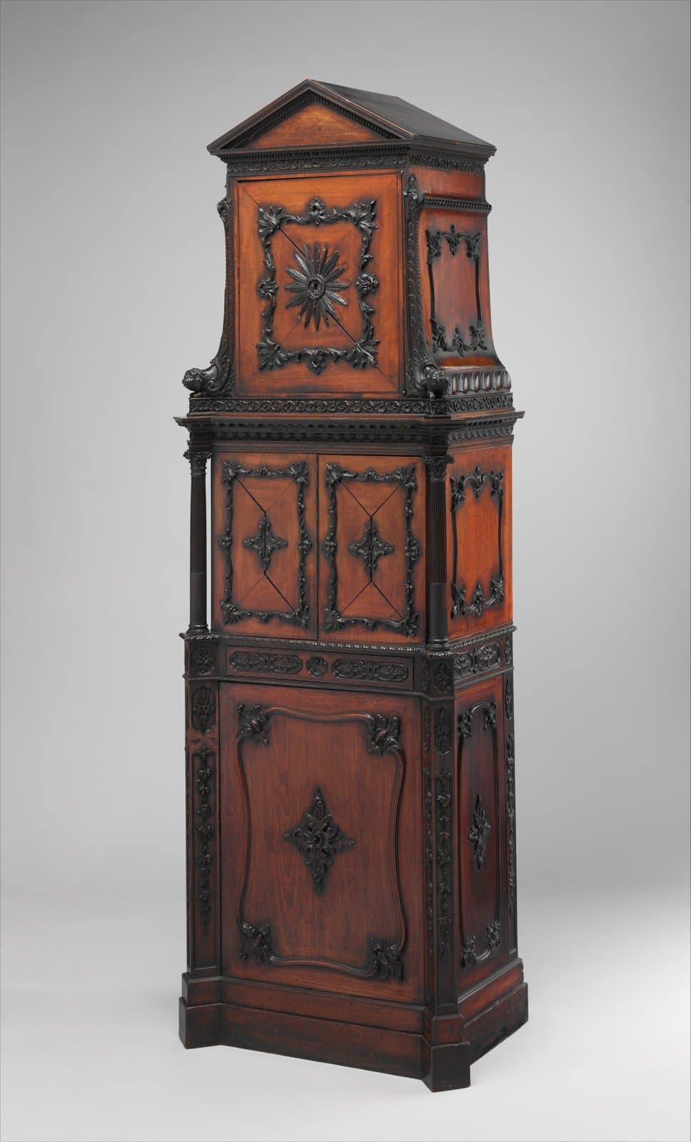 Tall mahogany medal cabinet with carved and applied decoration and a carved Garter star on the upper door, 1760 to 1761, attributed to William Vile and John Cobb