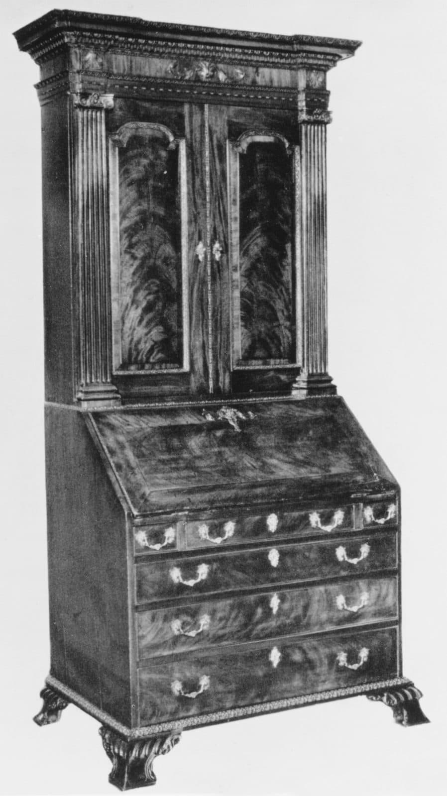 Mahogany bureau bookcase of about 1755 with fluted pilasters, veneered upper doors, a fall front over four drawers and carved feet