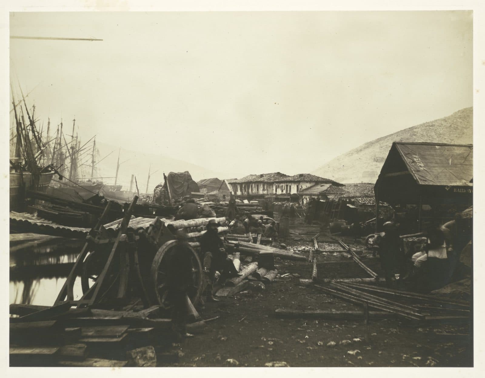 Timber, wheels and stores landed on a quay beside sailing ships, photographed by Roger Fenton in 1855