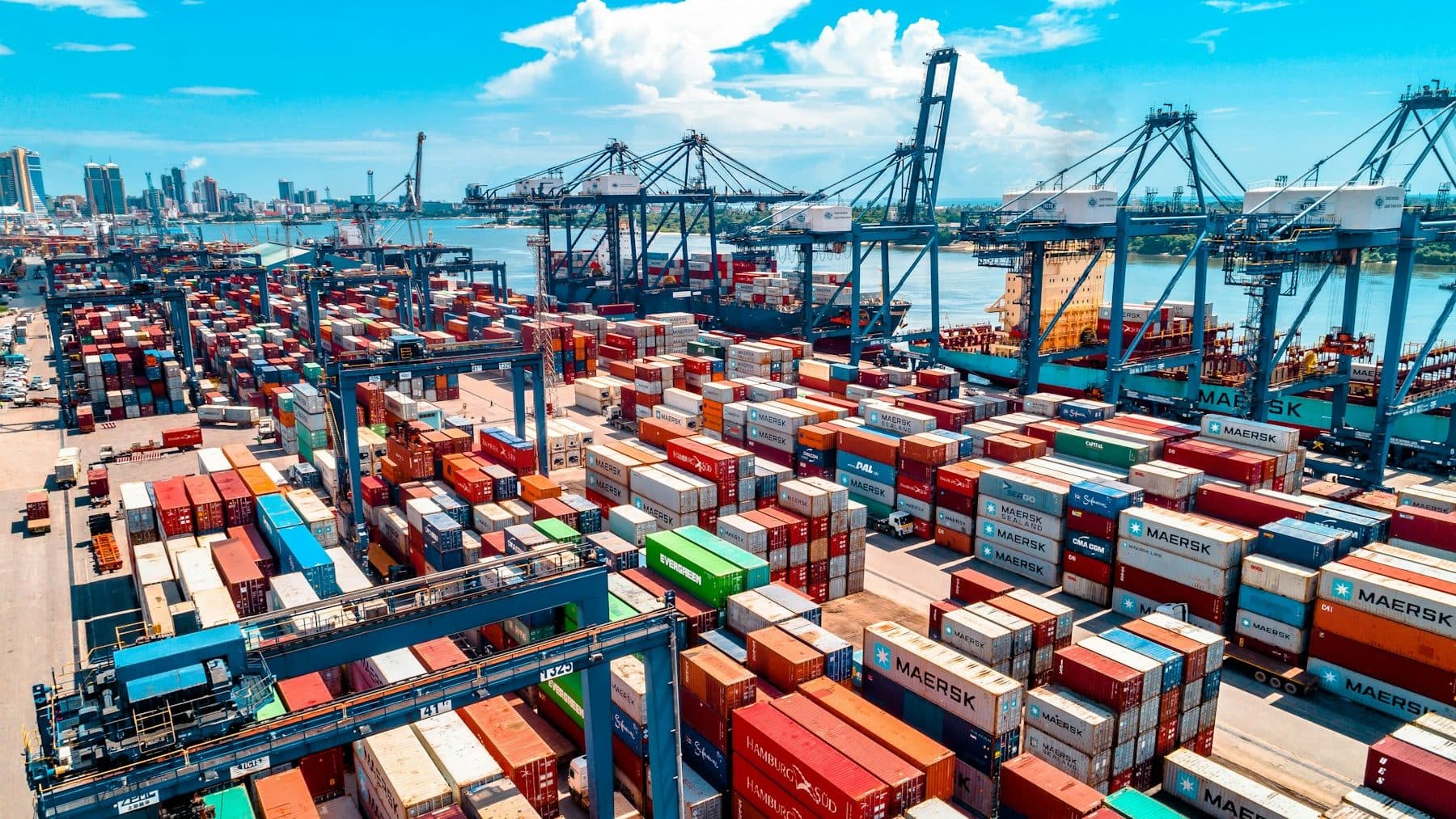 Stacked shipping containers and cranes at a container port